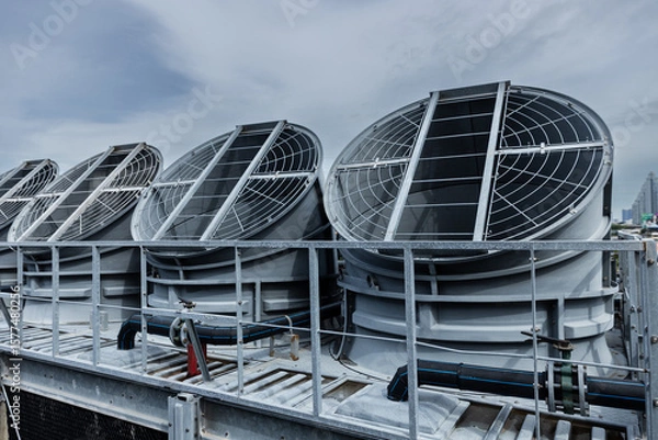 Fototapeta Cooling fans are installed on rooftop of large commercial building. Maintaining air circulation and temperature control. Tower air chiller HVAC.