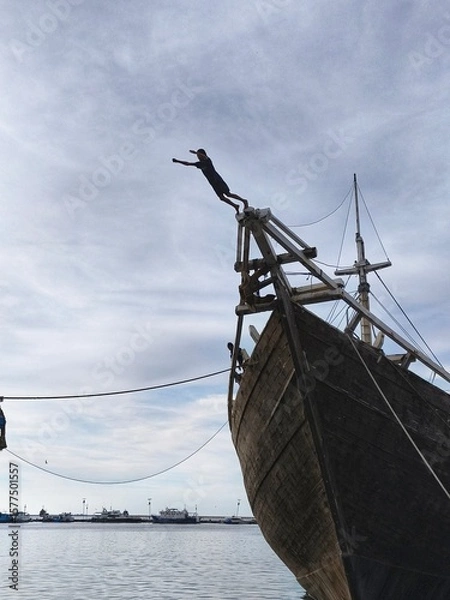 Obraz a coastal child who jumped from a traditional boat made of wood