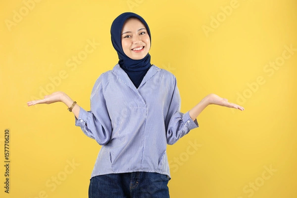 Fototapeta Cheerful Young Asian woman in Blue Shirt and Navy Hijab Celebrating Success