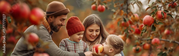 Fototapeta Happy family with two children picking and eating apples together in a colorful autumn orchard