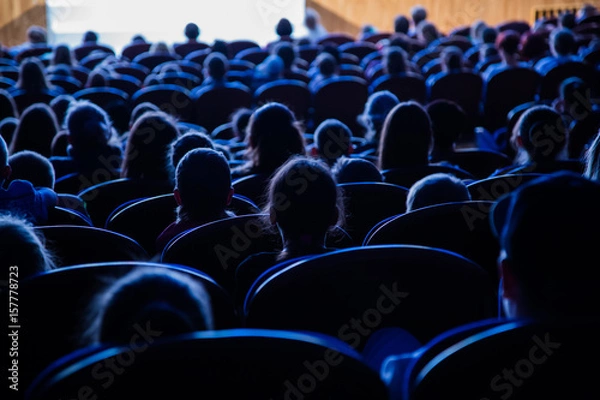 Fototapeta People, children, adults, parents in the theater watching the performance. People in the auditorium looking at the stage. Shooting from the back