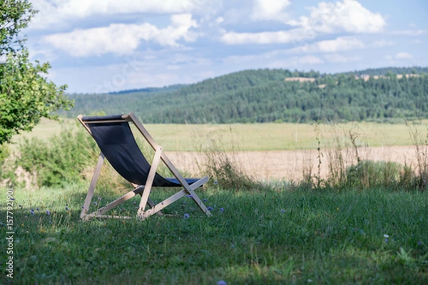Obraz camping chair on grass field and hills in background