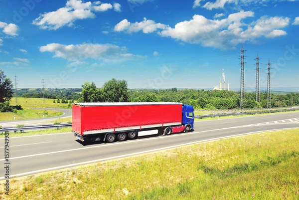 Obraz A truck driving through a landscape under high voltage pylons