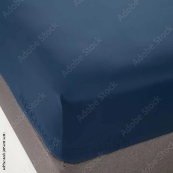 Fototapeta Solid navy blue fitted sheet on a bed with a neutral-toned mattress showing a cozy bedroom setup.