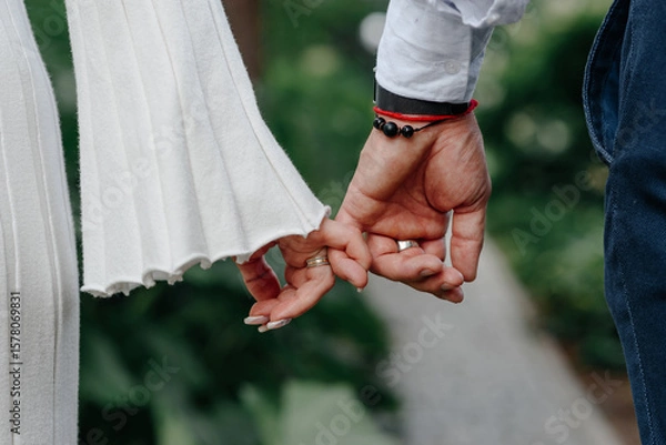 Fototapeta close-up view of couple holding hands, young beautiful caucasian man and woman take each other hands, walking on pathway in park in summer, love and family concept, selective focus