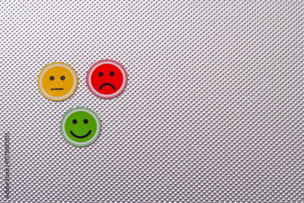 Fototapeta Three round emoji faces in red, yellow, and green representing sad, neutral, and happy emotions on a metallic textured background, symbolizing feedback or mood scale