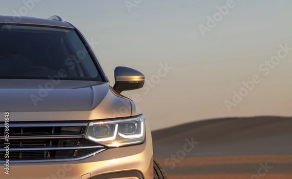 Fototapeta A gray SUV stands parked among the towering sand dunes of the Namib Desert under a dramatic cloudy sky. A bold visual of strength, solitude, and desert adventure.