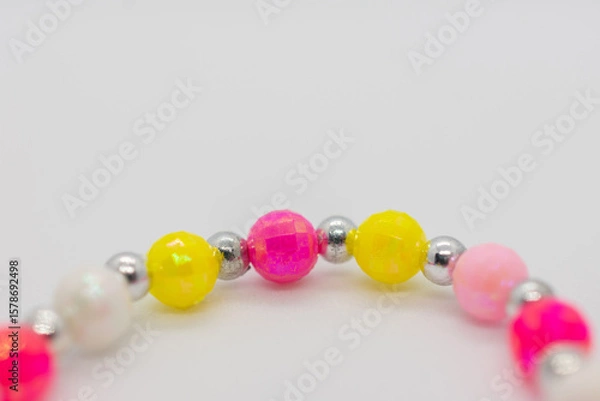 Fototapeta Colorful string of beads with a silver bead in the middle. The beads are in various colors and sizes, creating a vibrant and eye-catching design.