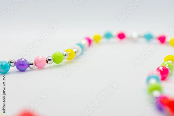 Fototapeta Colorful necklace with many different colored beads. The beads are of various sizes and colors, and they are arranged in a line. The necklace appears to be made of glass beads, and it is a beautiful.