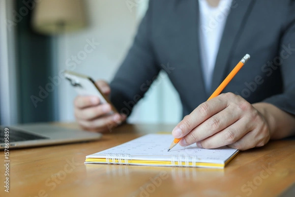 Fototapeta close up businessman hand use pencil to write or mark on important date of conference meeting manage timetable each day  in office private room for for planning work and life concept