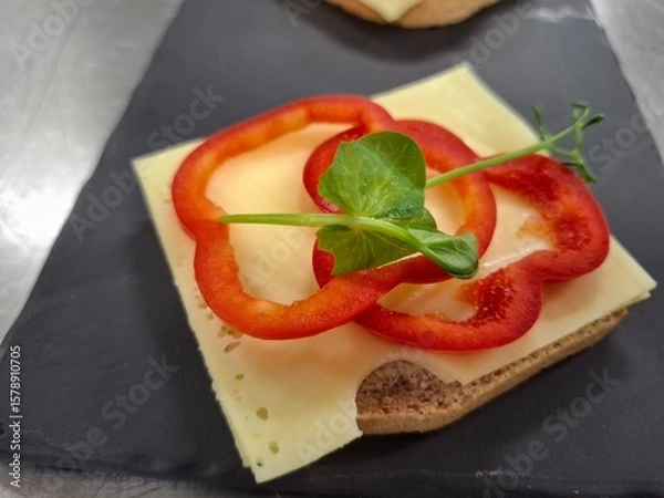 Fototapeta Delicious Open-Faced Sandwich with Cheese, Red Pepper, and Fresh Greens Garnish