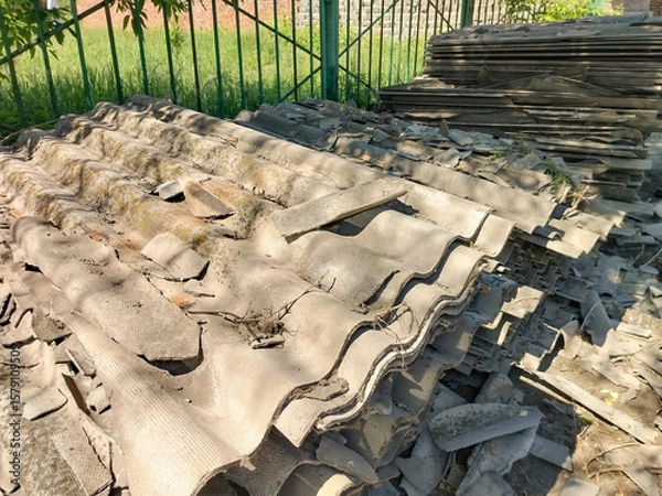 Fototapeta Old gray slate, stacked in uneven piles and broken into pieces of different shapes and sizes. Construction waste after roof repair