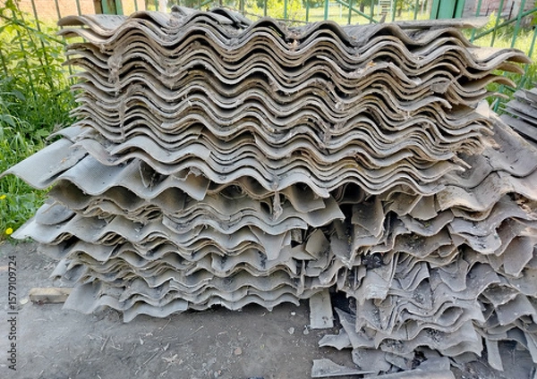 Fototapeta Old gray slate, stacked in uneven piles and broken into pieces of different shapes and sizes. Construction waste after roof repair
