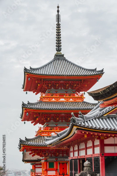 Fototapeta Stunning view of Kiyomizu-dera Temple's three-story pagoda in Kyoto, Japan.  Intricate architecture, vibrant red and gray, against a cloudy sky. A captivating example of traditional Japanese design.