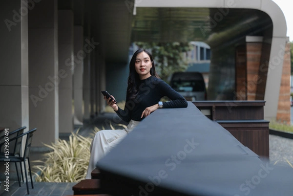 Fototapeta Businesswoman using smartphone while sitting in a modern building