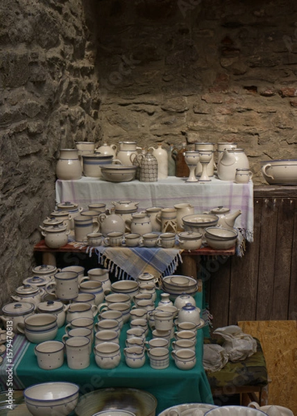 Fototapeta Handmade ceramic mugs, bowls and pots at the castle fair. Period ceramic dishes on a stand. Replicas of ancient ceramic objects.