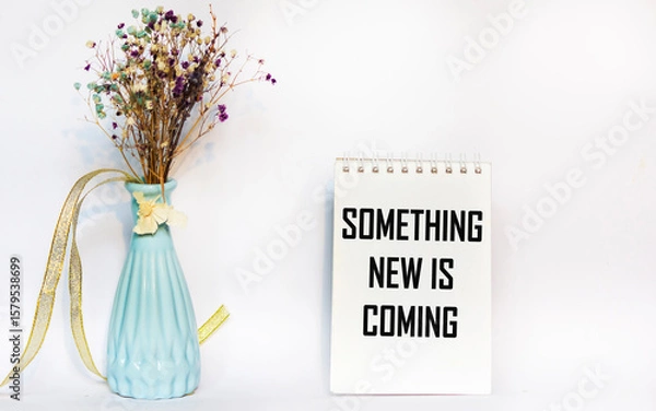 Fototapeta The message "Something new is coming" is written on a notepad page on a white background.