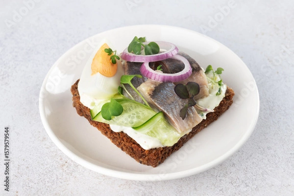 Fototapeta Traditional Danish open sandwich smorrebrod with herring, egg, cucumber, onion on rye bread. Scandinavian cuisine.
