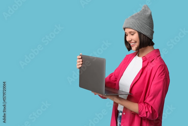 Obraz Beautiful young woman working with modern laptop on blue background
