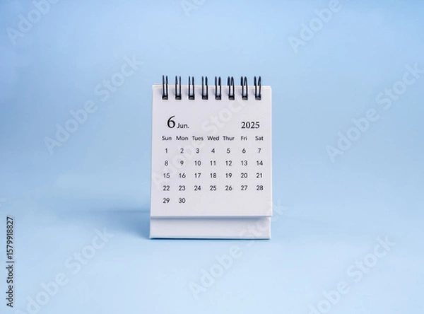 Obraz A June 2025 desk calendar for organizer to plan and reminder standing, isolated on blue horizontal background, minimalist. White small table calendar with the page of the sixth month, minimal style.