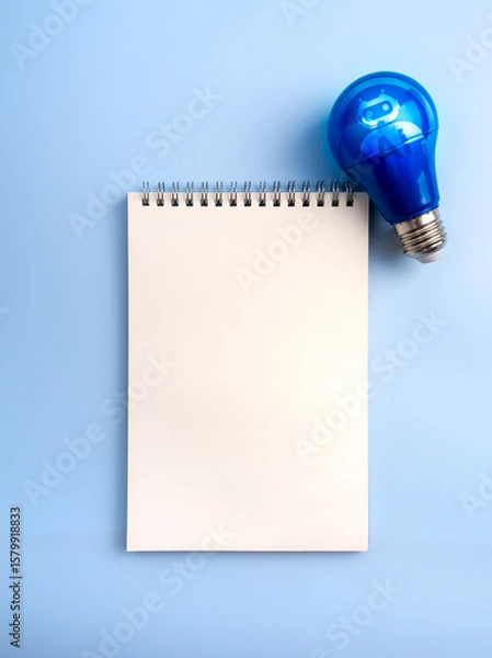 Obraz Creative idea and inspiration with AI assistant service technology concept. AI chatbot icon on electric lightbulb and mockup empty white blank space of vertical spiral notebook page, blue background.
