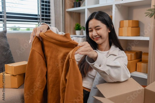Fototapeta she is happily packing products into boxes to be sent to customers, an entrepreneur is preparing products to be sent to buyers, parcel, sme, package, small business, preparation