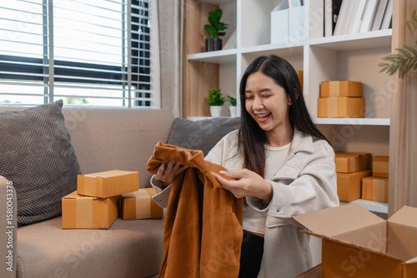 Fototapeta she is happily packing products into boxes to be sent to customers, an entrepreneur is preparing products to be sent to buyers, parcel, sme, package, small business, preparation