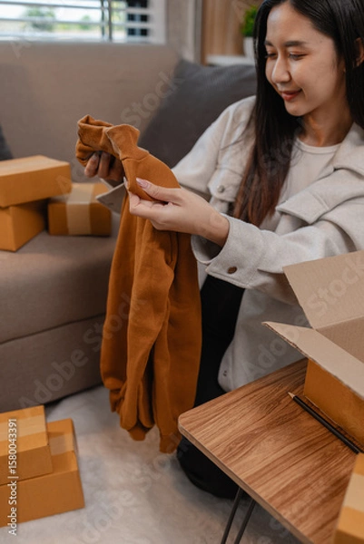 Fototapeta she is happily packing products into boxes to be sent to customers, an entrepreneur is preparing products to be sent to buyers, parcel, sme, package, small business, preparation