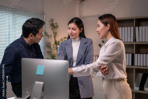 Fototapeta Three people are standing in front of a computer monitor
