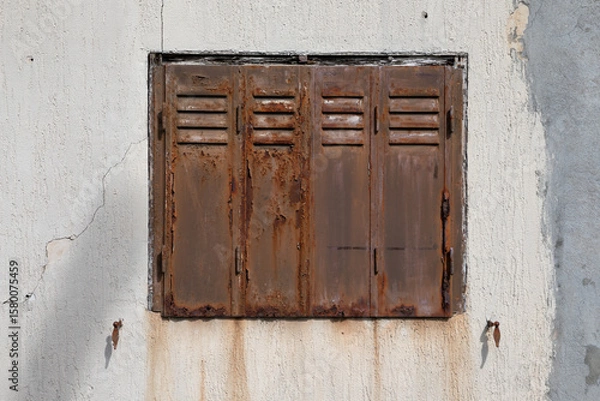 Fototapeta old steel rusty closed shutters on home facade