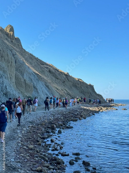 Obraz A group of tourists traveling walk the sea beach