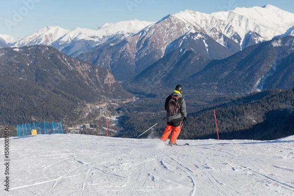 Obraz Skiers, snowboarders skiing in a mountain resort
