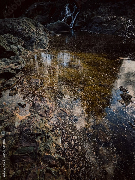 Fototapeta A clear lake with a rocky shore and a view of the mountains. A serene lake with crystal clear water and a rocky shore, surrounded by high mountains and evergreen trees.