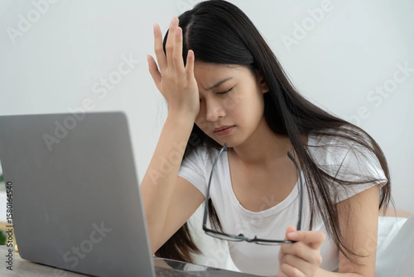 Fototapeta Eye problems, Asian women with tired and irritated eyes, eye rubbing, dry, eye pain after work, migraine, headache, blurred vision, photophobia, working in the dark, blue light from computer screens