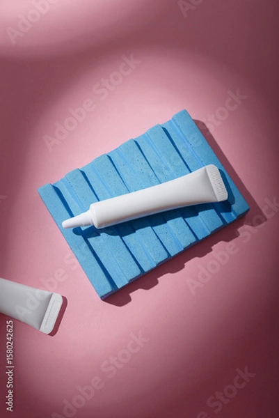Fototapeta Two white narrow unbranded cosmetics tubes mockup on pink background, harsh light with shadows. Beauty product template. Copy space, top view, flat lay