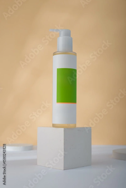 Fototapeta Dispenser Cosmetics bottle mockup on concrete cube stand, yellow background. Unbranded beauty container, blank green label template. copy space