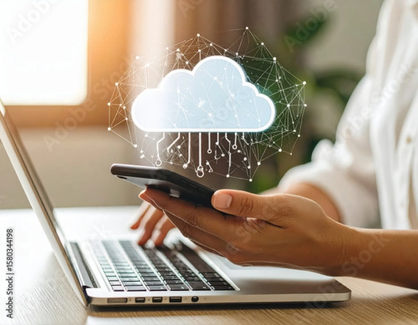 Obraz Photography of a person using the phone and labtop with cloud icon on the screen.