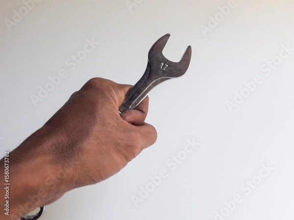 Fototapeta A man's hand holding a ring spanner, isolated on a white background, also known as a combination wrench.
