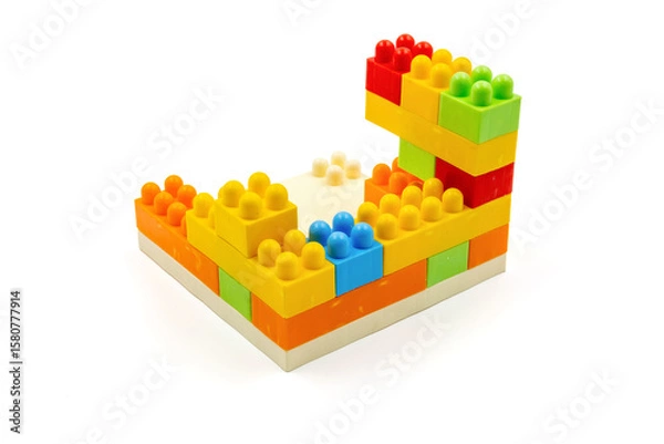 Fototapeta Colorful plastic building blocks assembled into a structure on white background