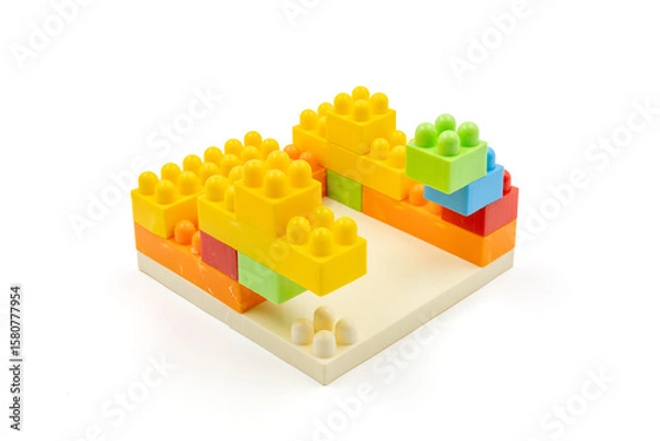 Fototapeta Colorful plastic building blocks assembled into a structure on white background