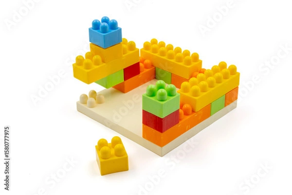 Fototapeta Colorful plastic building blocks assembled into a structure on white background