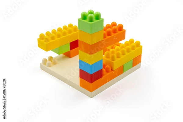 Fototapeta Colorful plastic building blocks assembled into a structure on white background