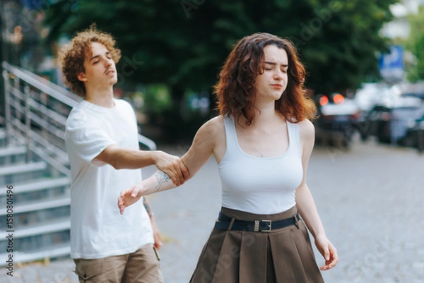 Fototapeta Man argues with upset girlfriend trying to explain himself on the street