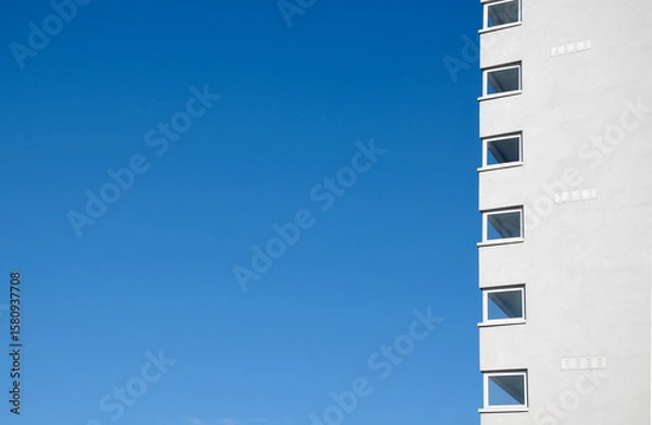 Fototapeta Abstract view of a high rise residential apartment block against a clear blue sky.