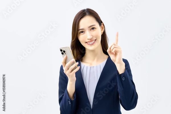 Obraz スマホを持って説明するスーツの若い女性
ビジネス