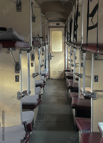 Fototapeta Interior of an old Soviet-style sleeper train carriage with narrow corridor and open bunk beds. The photo shows the typical layout of a compartment platzkart used in Eastern European rail travel