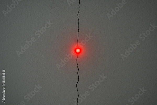 Fototapeta Red Laser Dot Aligned on Wall Crack – Symbol of Targeting Tension and Precision
