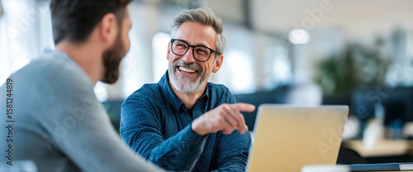 Fototapeta Collaboration and smiles: Two colleagues in modern workspace collaborate, smiling and engaging. A scene that evokes a sense of camaraderie and teamwork 