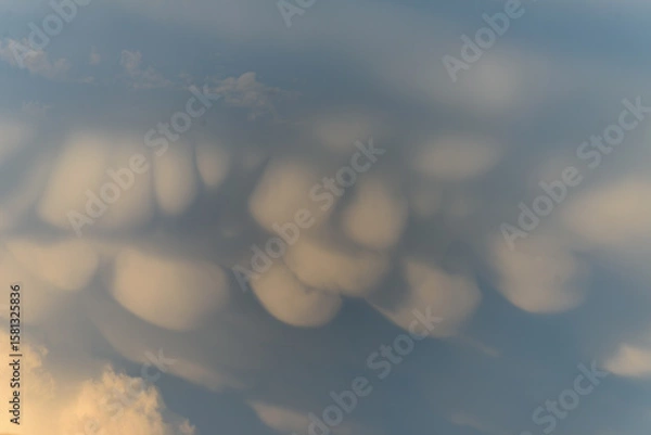Fototapeta Unique cloud formations display dramatic textures during sunset over the landscape