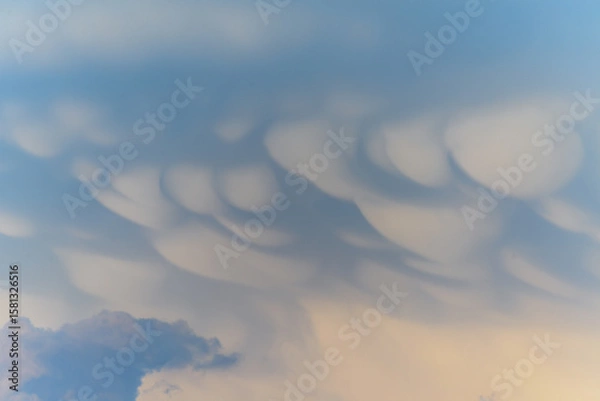 Fototapeta Unique cloud formations display dramatic textures during sunset over the landscape